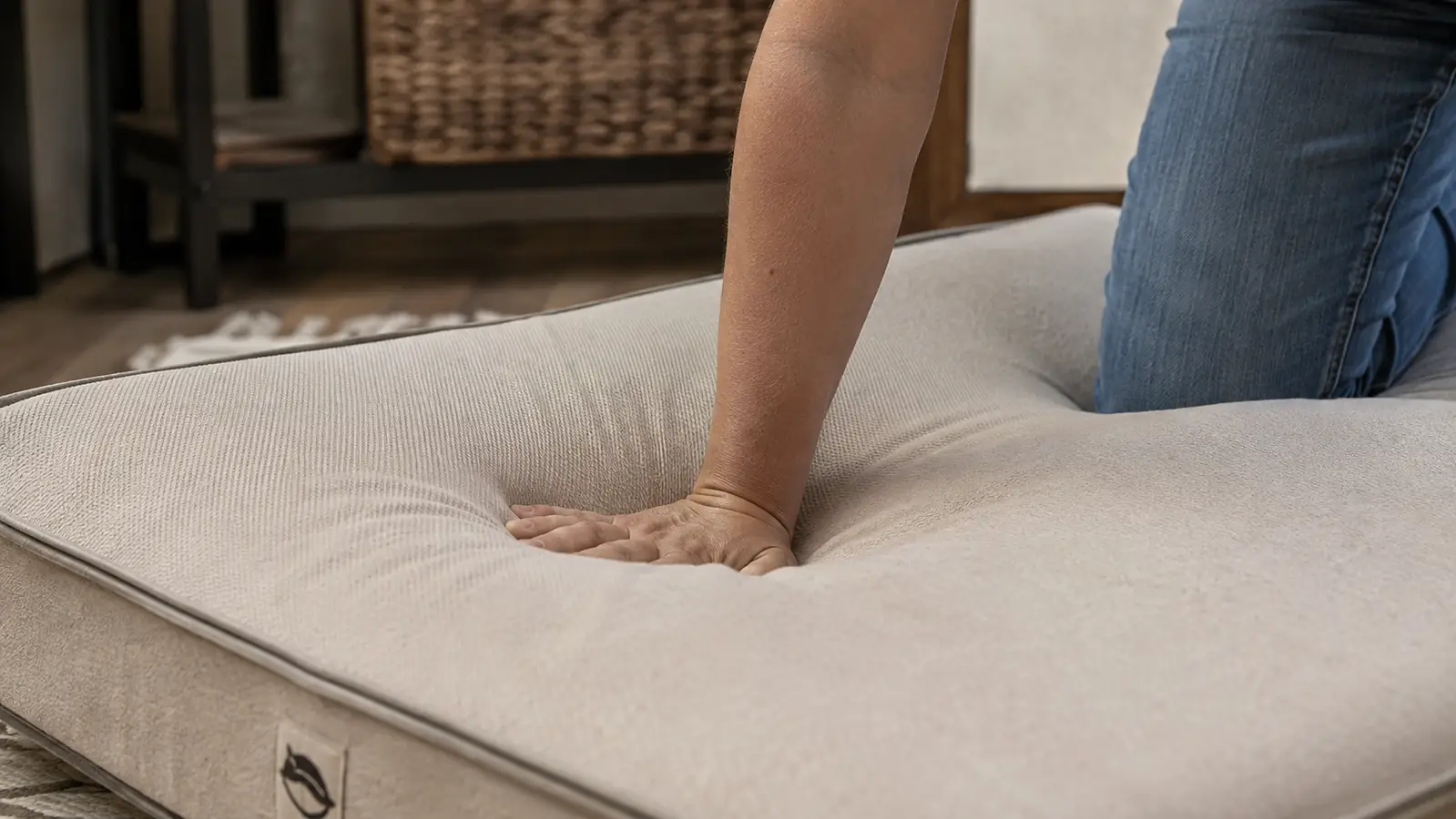 A person pressing a hand into the thick foam surface of a dog bed to show its support
