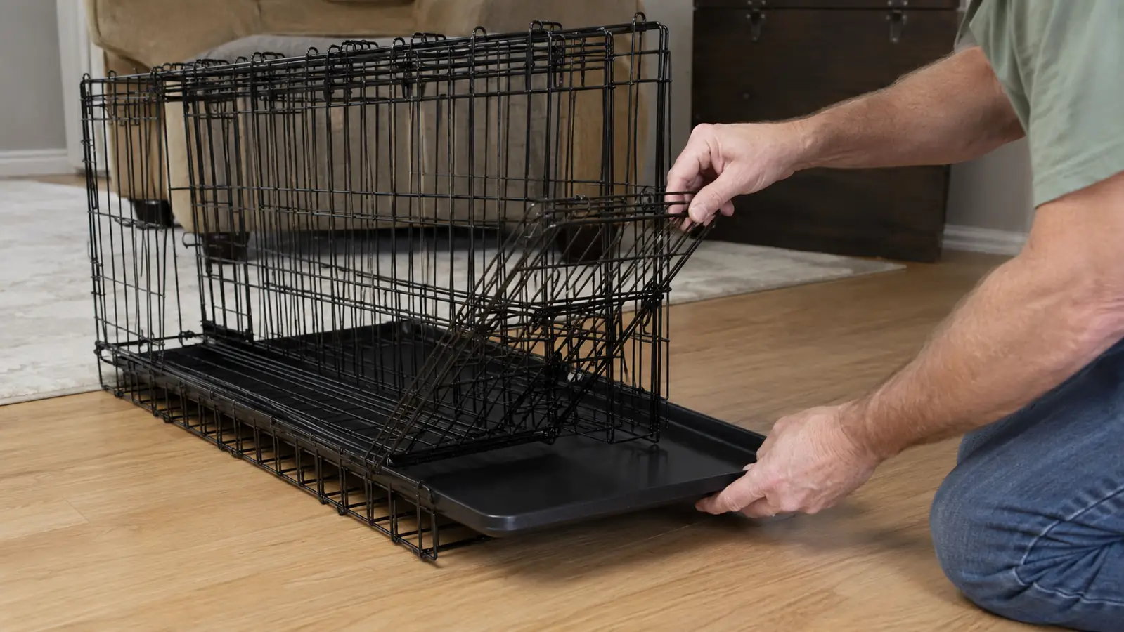Hands folding down the side panel of a wire dog crate on a living room floor